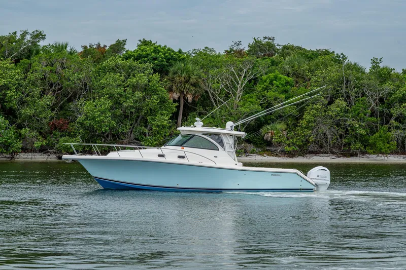 Bottoms Up II Yacht Photos Pics 2009 Pursuit OS 375 Offshore boat cruising near lush green shoreline.