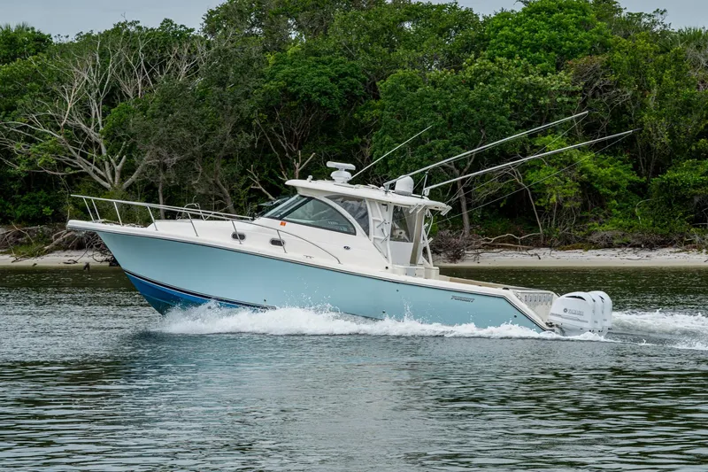 Bottoms Up II Yacht Photos Pics 2009 Pursuit OS 375 Offshore boat cruising near lush green shoreline.