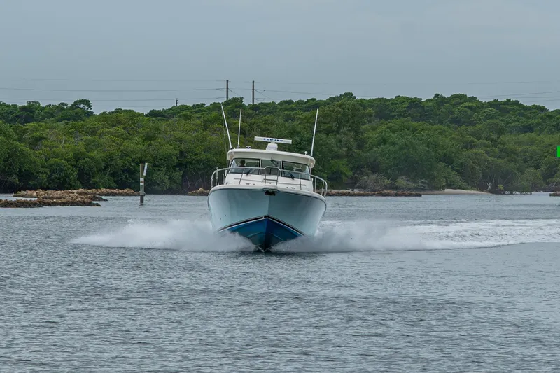 Bottoms Up II Yacht Photos Pics 2009 Pursuit OS 375 Offshore boat cruising on a calm waterway with lush greenery.