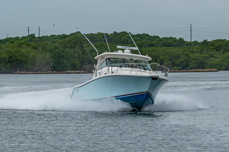 Bottoms Up II Yacht Photos Pics 2009 Pursuit OS 375 Offshore boat cruising on water with lush green background.