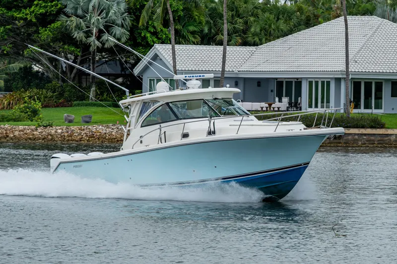 Bottoms Up II Yacht Photos Pics 2009 Pursuit OS 375 Offshore boat cruising near waterfront home, surrounded by lush greenery.