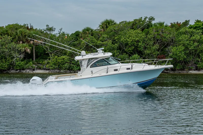 Bottoms Up II Yacht Photos Pics 2009 Pursuit OS 375 Offshore boat cruising on a calm waterway with lush greenery.