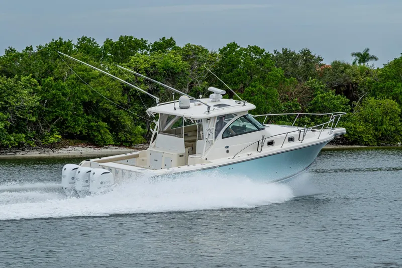 Bottoms Up II Yacht Photos Pics 2009 Pursuit OS 375 Offshore boat cruising on water near lush greenery.