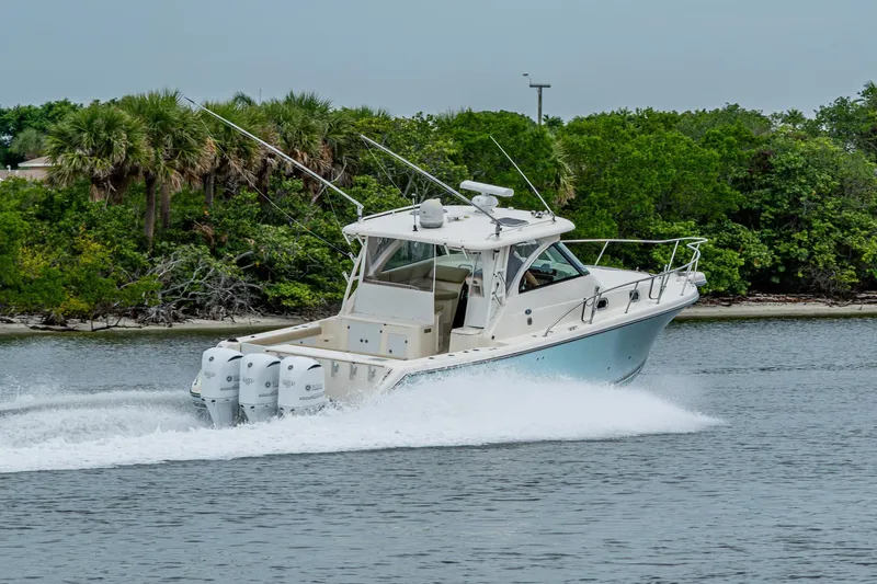 Bottoms Up II Yacht Photos Pics 2009 Pursuit OS 375 Offshore boat cruising near lush green shoreline.