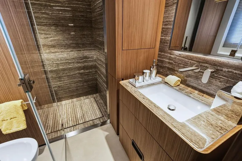 Randy Beth Yacht Photos Pics Luxurious bathroom with wood accents, marble sink, and glass shower in a 2018 Custom Line 120 yacht.