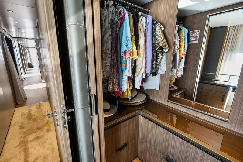 Randy Beth Yacht Photos Pics Luxurious yacht interior with a wooden wardrobe, colorful clothes, and a hallway view.