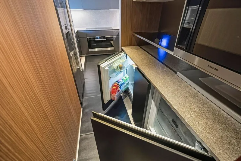 Randy Beth Yacht Photos Pics Modern kitchen with open fridge, sleek appliances, and wood paneling in a Custom Line 120 yacht.