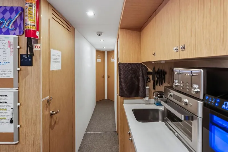 Randy Beth Yacht Photos Pics Compact yacht kitchen with modern appliances, wooden cabinets, and hallway view. Custom Line 120, 2018.