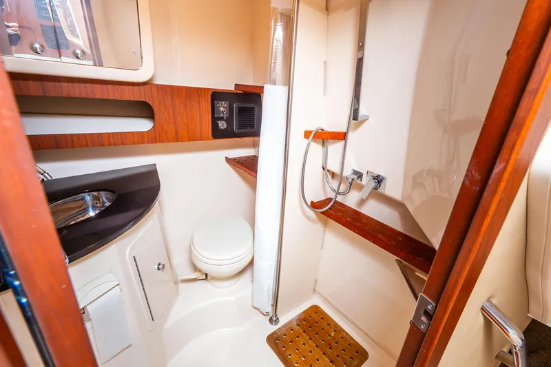  Yacht Photos Pics 2020 Grady-White 370 Express boat bathroom with shower, sink, and wooden accents.