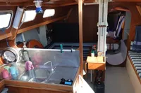 Cozy boat interior with kitchen, seating, and storage, featuring wooden design elements.