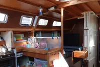 Cozy boat interior with wooden finish, kitchen area, and natural light from windows.