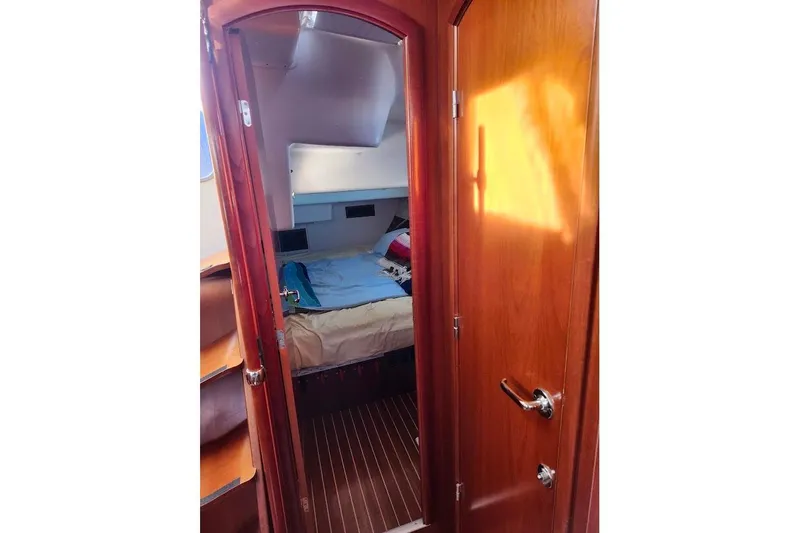 Rick B Yacht Photos Pics Interior cabin of 2006 Beneteau 473 sailboat with wooden door and cozy bed.
