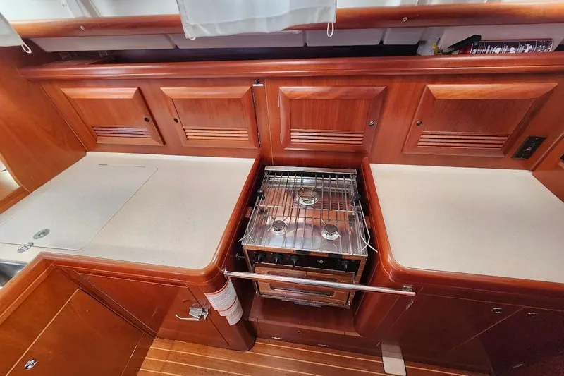 Rick B Yacht Photos Pics 2006 Beneteau 473 yacht kitchen with wooden cabinets and a compact stove.