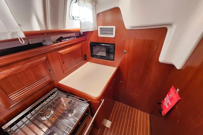 Rick B Yacht Photos Pics Interior of 2006 Beneteau 473 yacht kitchen with stove, microwave, and wooden cabinetry.