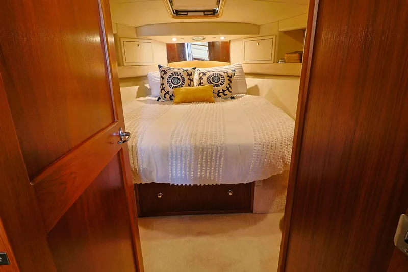  Yacht Photos Pics Cozy bedroom in 2000 Riviera Flybridge Convertible yacht with elegant bedding and wooden accents.