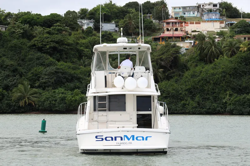  Yacht Photos Pics Riviera Flybridge Convertible 2000 boat on water, lush green hillside background.