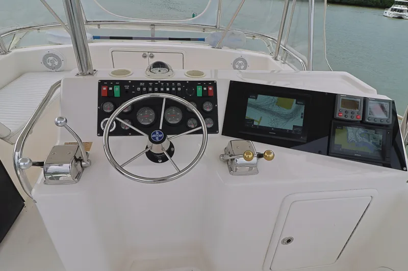  Yacht Photos Pics Control panel of a 2000 Riviera Flybridge Convertible yacht with steering wheel and navigation screens.