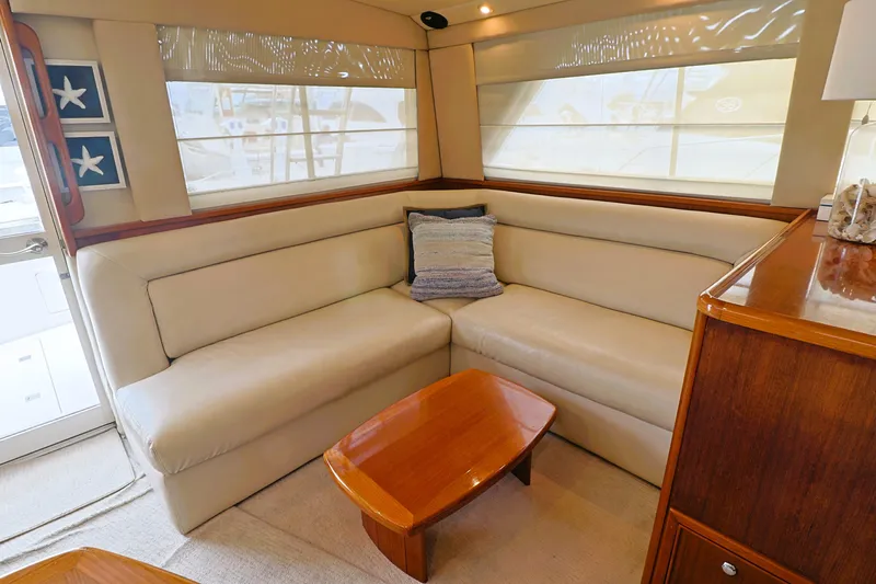  Yacht Photos Pics Luxurious interior of 2000 Riviera Flybridge Convertible yacht with beige seating and wooden table.