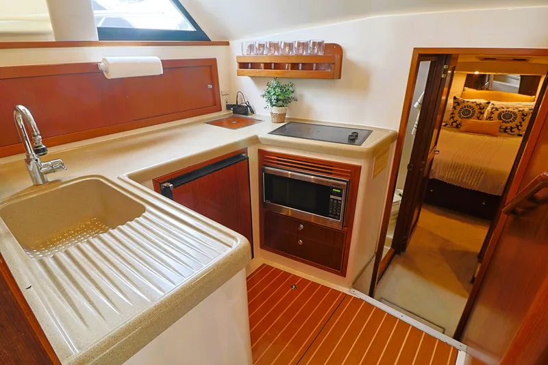  Yacht Photos Pics 2000 Riviera Flybridge Convertible yacht kitchen with modern amenities and cozy bedroom.