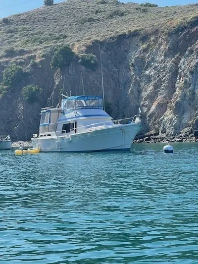 Fishers Folly IV Yacht Photos Pics 1988 Offshore Yachts 48 Yachtfisher anchored near rocky coastline.