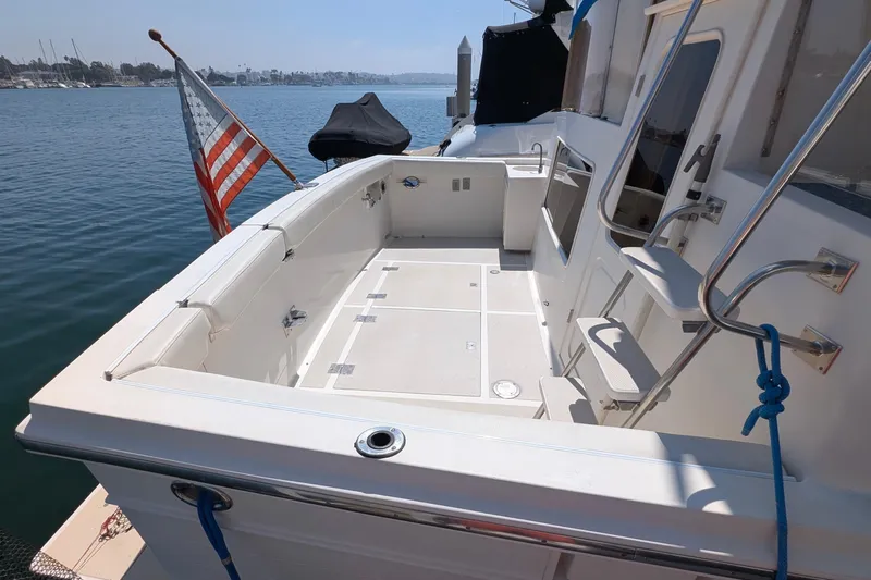 Fishers Folly IV Yacht Photos Pics 1988 Offshore Yachts 48 Yachtfisher deck with American flag, docked by calm waters.