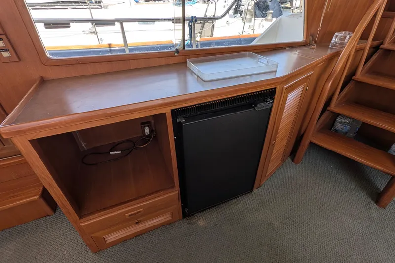 Fishers Folly IV Yacht Photos Pics Interior of 1988 Offshore Yachts 48 Yachtfisher with wooden cabinetry and mini fridge.