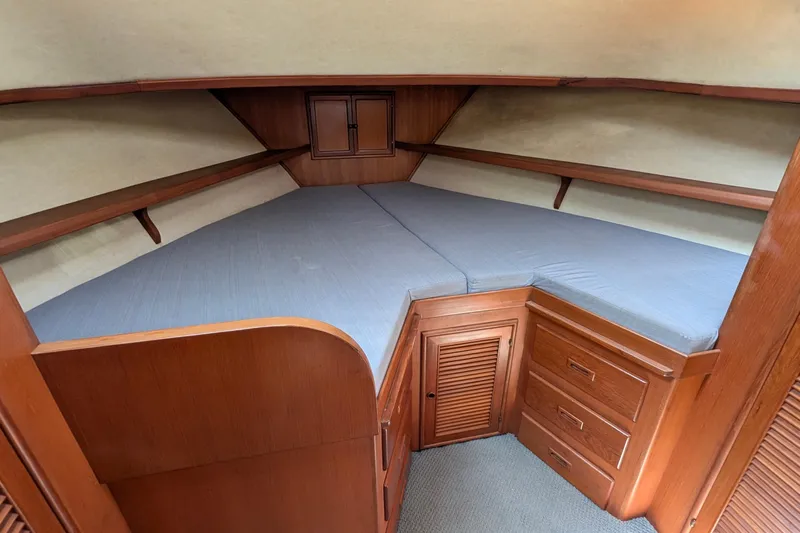 Fishers Folly IV Yacht Photos Pics 1988 Offshore Yachts 48 Yachtfisher cabin with wooden storage and blue bedding.