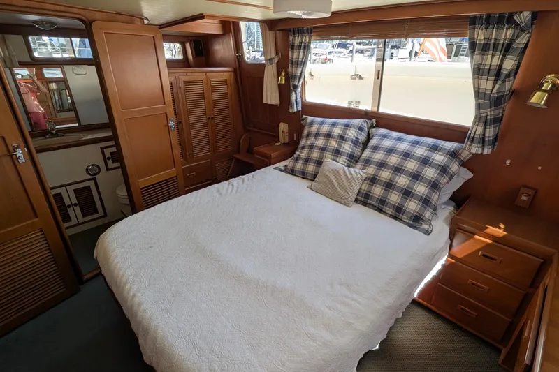Fishers Folly IV Yacht Photos Pics Cozy bedroom in 1988 Offshore Yachts 48 Yachtfisher with plaid accents and wooden cabinetry.