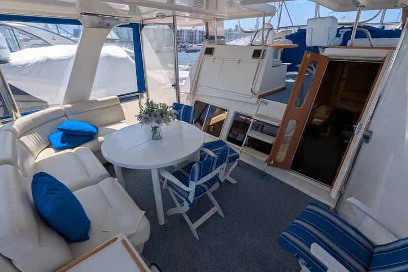 Fishers Folly IV Yacht Photos Pics Luxurious 1988 Offshore Yachts 48 Yachtfisher interior with seating and table, docked at marina.