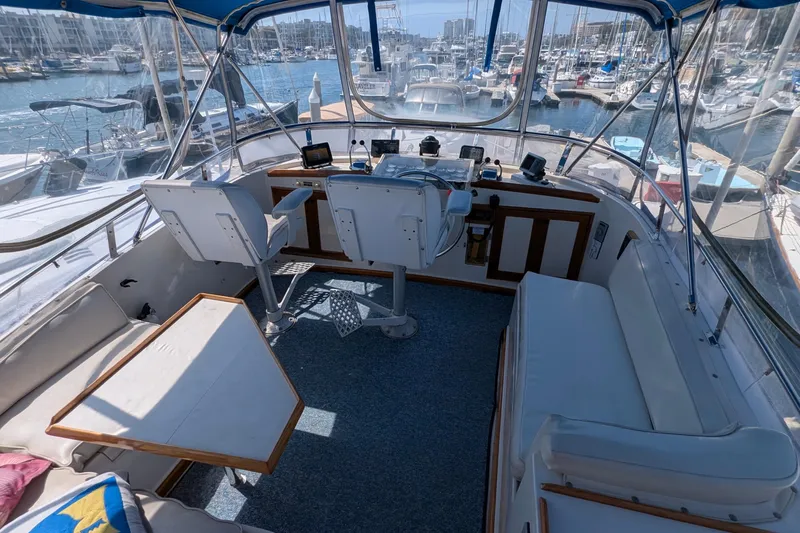 Fishers Folly IV Yacht Photos Pics Interior view of 1988 Offshore Yachts 48 Yachtfisher helm with marina backdrop.