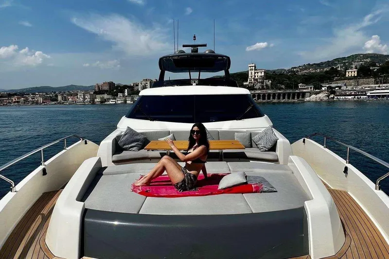 E3 Yacht Photos Pics 2019 Ferretti Yachts 850 on water, woman relaxing on deck, coastal city backdrop.
