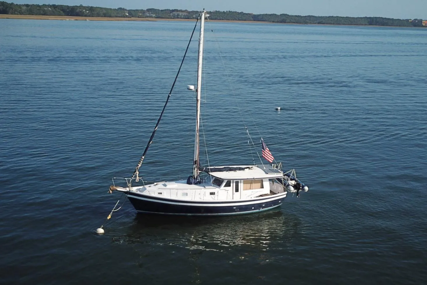 1979 Schucker 436 Motorsailor anchored on calm water with American flag.