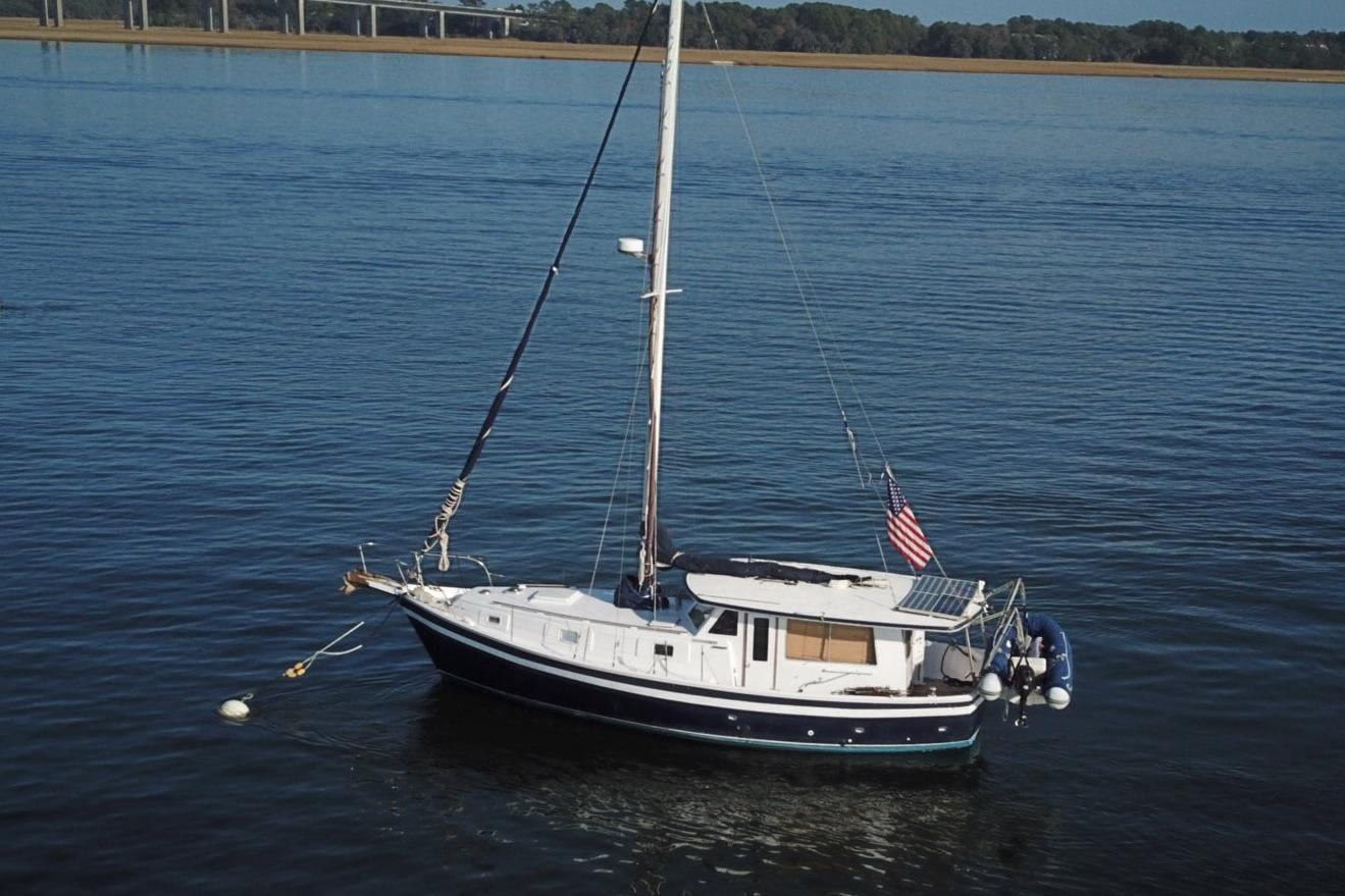 1979 Schucker 436 Motorsailor anchored on calm water with American flag.
