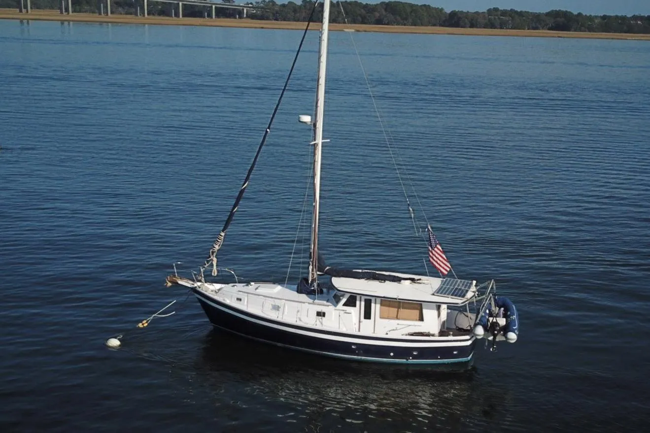 1979 Schucker 436 Motorsailor anchored on calm water with American flag.