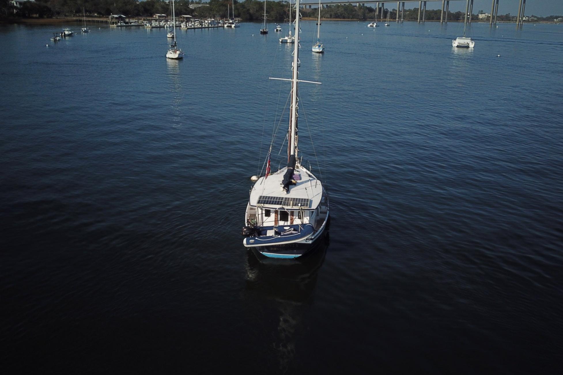 1979 Schucker 436 Motorsailor on calm water with distant boats and shoreline.