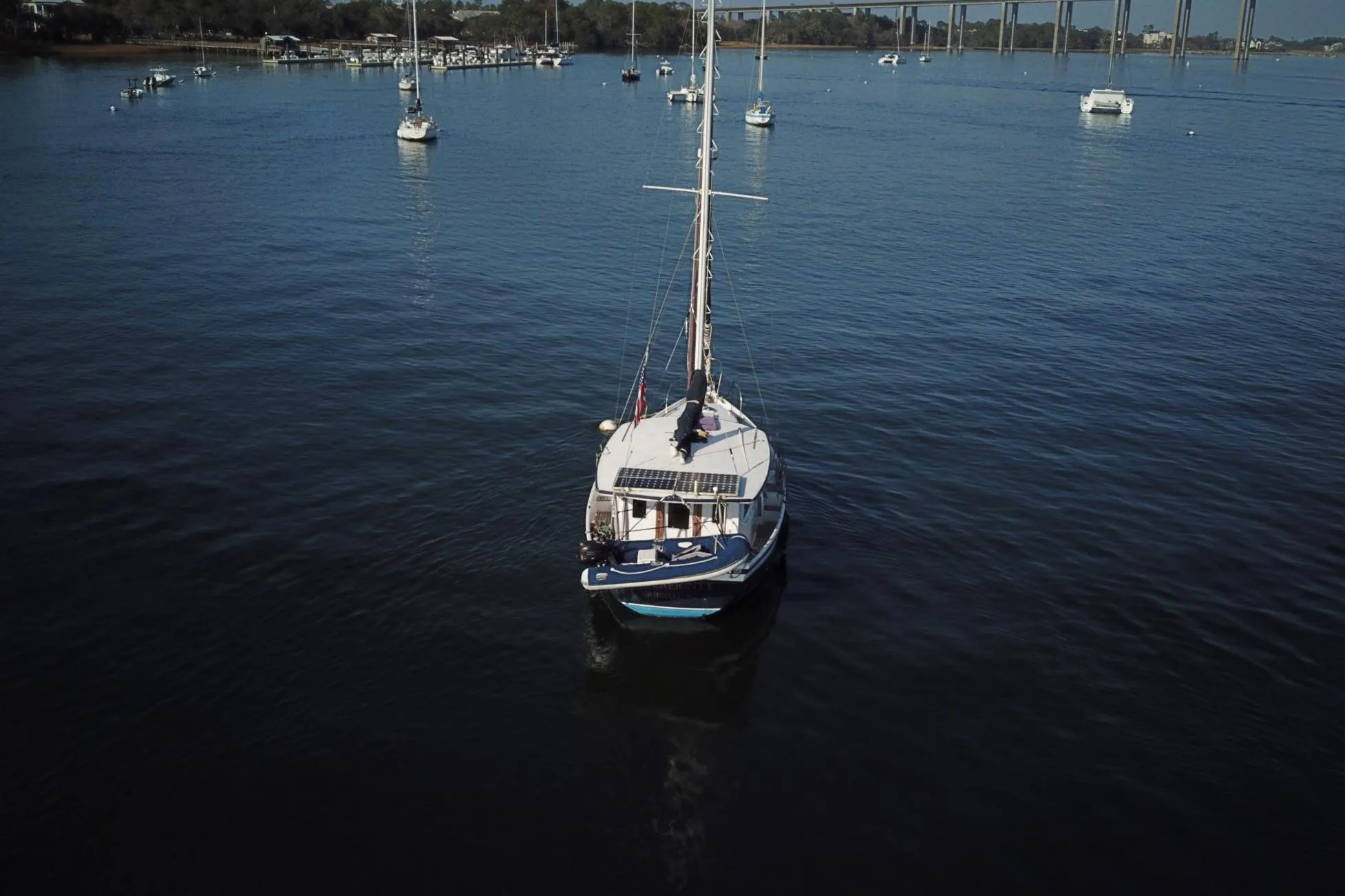 1979 Schucker 436 Motorsailor on calm water with distant boats and shoreline.