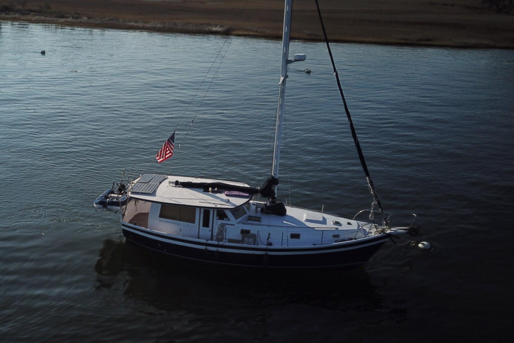 1979 Schucker 436 Motorsailor with American flag on calm water.