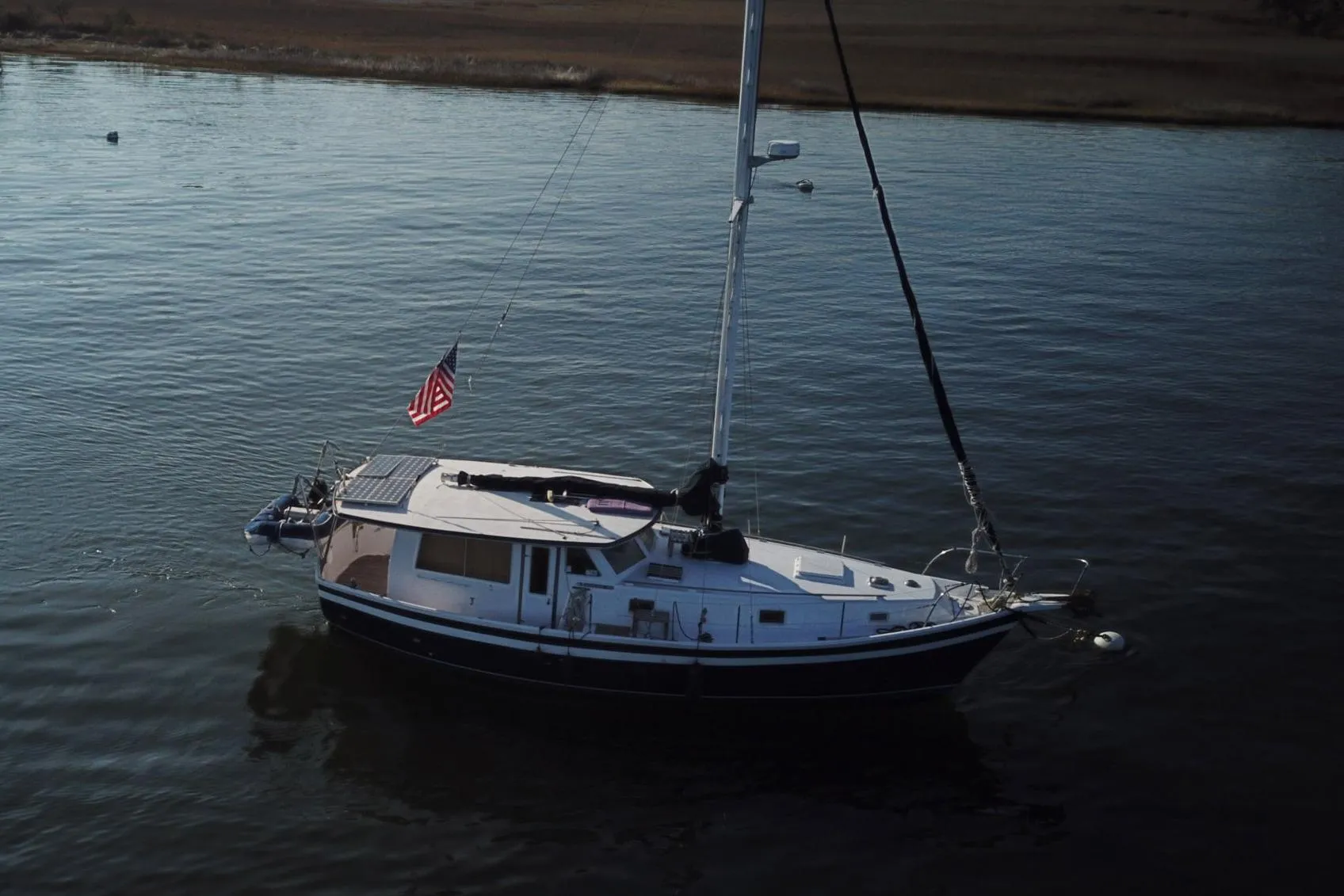 1979 Schucker 436 Motorsailor with American flag on calm water.