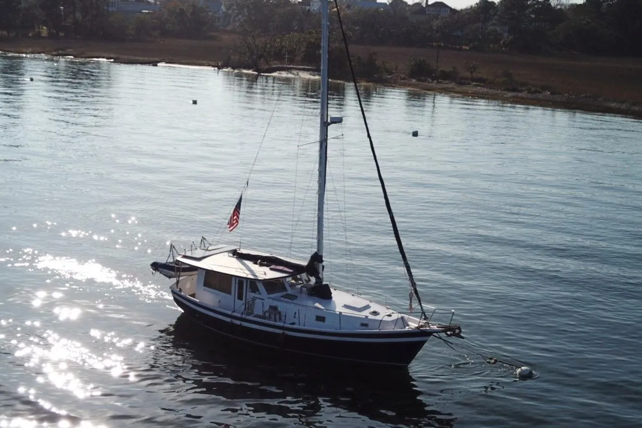 1979 Schucker 436 Motorsailor on calm water, reflecting sunlight.
