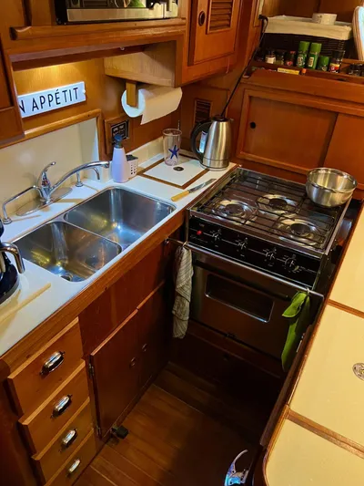 Aries Yacht Photos Pics Compact kitchen in 1982 Sea Star 46 yacht with stove, sink, and wooden cabinetry.