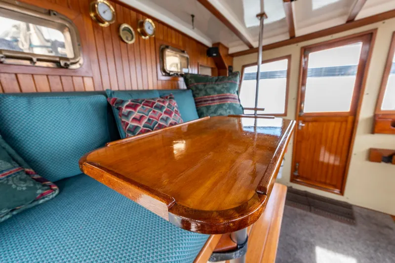Points North III Yacht Photos Pics Interior of 1986 Kadey-Krogen 42 yacht with wooden table and blue seating.