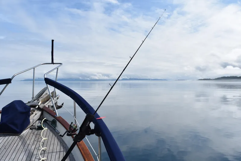 Points North III Yacht Photos Pics Bow of 1986 Kadey-Krogen 42 with fishing rod on calm sea under cloudy sky.