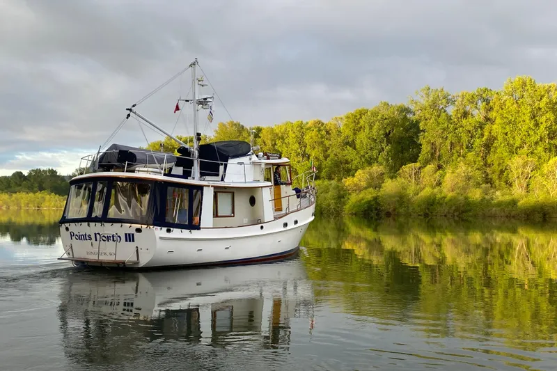 Points North III Yacht Photos Pics 1986 Kadey-Krogen 42 boat cruising on a serene river with lush green trees.