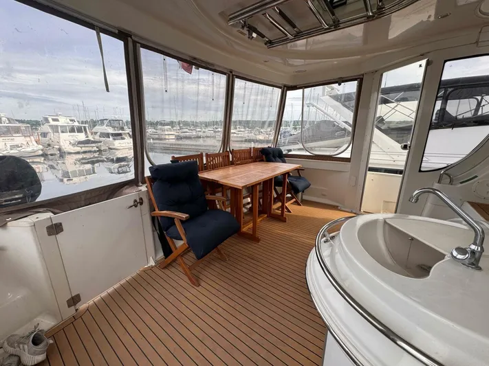  Yacht Photos Pics 2002 Carver 466 Motor Yacht interior with wooden table, cushioned chairs, and marina view.