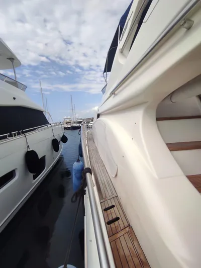  Yacht Photos Pics 2007 Azimut 62 yacht docked, showcasing sleek design and wooden deck under a partly cloudy sky.