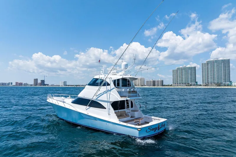 Sexy Lady Yacht Photos Pics 2017 Viking 62 Enclosed Bridge yacht cruising near coastal city skyline.