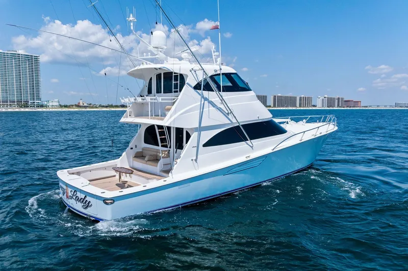 Sexy Lady Yacht Photos Pics 2017 Viking 62 Enclosed Bridge yacht cruising on blue ocean near city skyline.