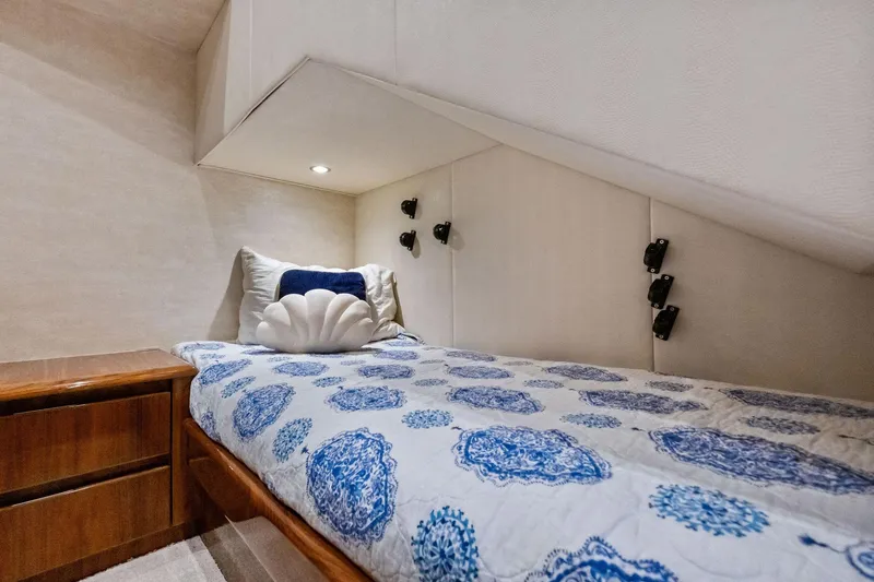Sexy Lady Yacht Photos Pics Cozy cabin interior of 2017 Viking 62 Enclosed Bridge with patterned bedding and wooden nightstand.