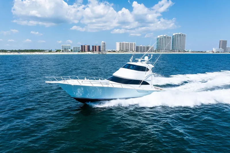 Sexy Lady Yacht Photos Pics 2017 Viking 62 Enclosed Bridge yacht cruising near a coastal city skyline.