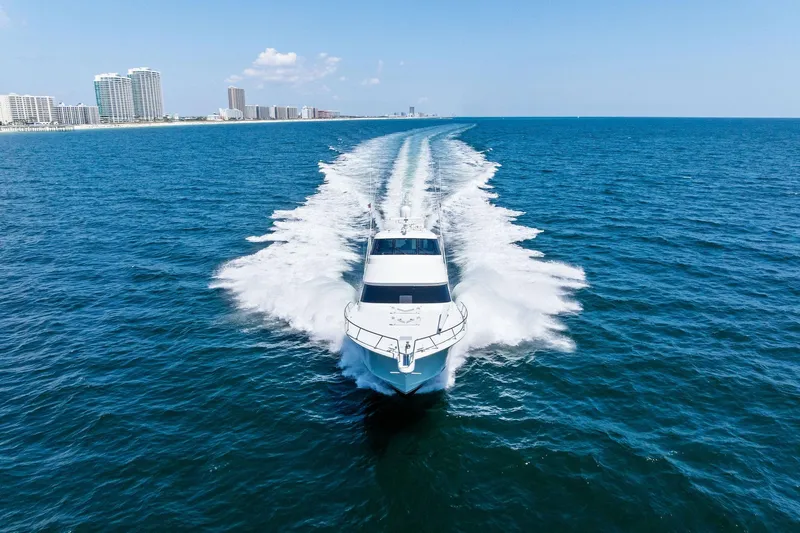 Sexy Lady Yacht Photos Pics 2017 Viking 62 Enclosed Bridge yacht cruising on open ocean near city skyline.